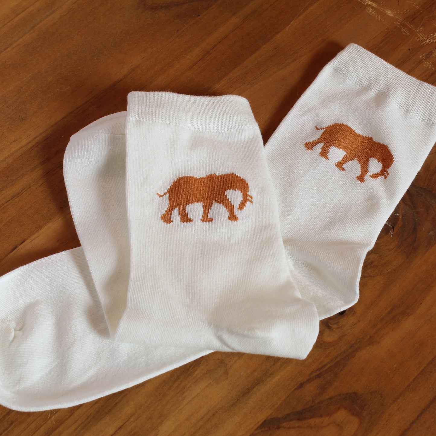 White socks with orange elephant design on a wooden surface