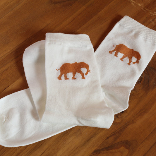 White socks with orange elephant design on a wooden surface